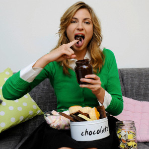 Portrait of woman sitting on couch eating sweets